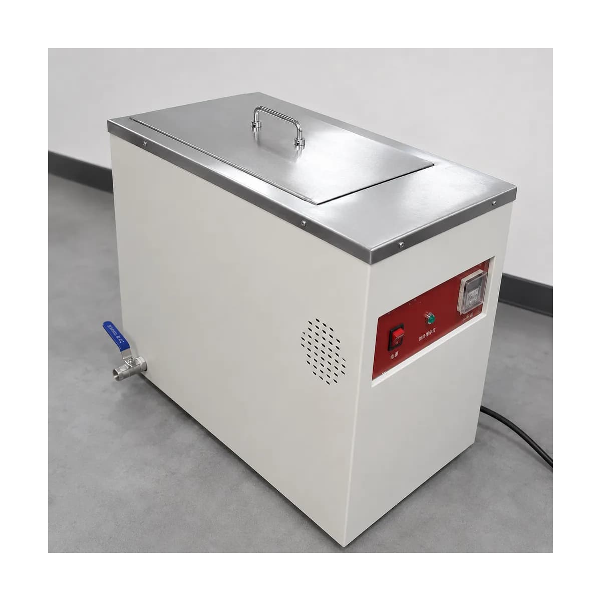Side angle of the real unit showing the stainless lid handle, blue-handled drain valve and ventilation grille
